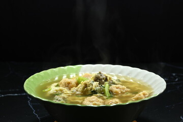Classic clear soup of poached egg and meat ball serving in the bowl. Famous soft and light breakfast menu in Asia restaurant. 