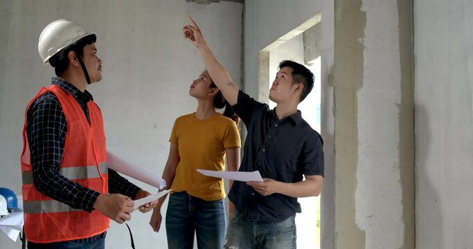 Asian male foreman worker talking with two client on new house building. That are angry dissatisfied about warehouse construction and discussing of commerce product in real state concept.