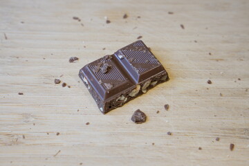 Close up top view of a chocolate bar with nuts on a wooden background