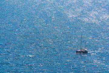 Distance shut taken by drone: View from above of a single floating sailing boat on tranquil waters....