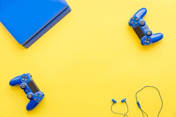 Top view of blue gaming controllers, a console and earphones. Virtual regality gaming accessories.