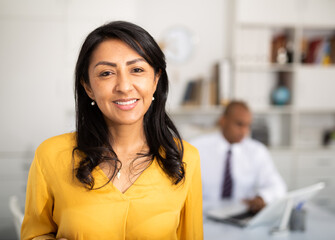 Portrait of smiling confident hispanic woman employee posing in light office interior