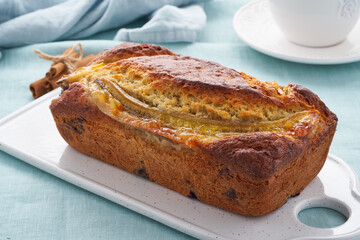 Banana bread, cake with banana. Whole loaf on cutting board. Morning breakfast with tea on blue...