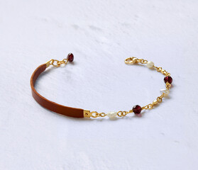 Brown leather strap bracelet with pearl and burgundy crystal beads.