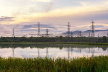 High-voltage transmission towers on the hill with reflection in the morning tranquil Mae Moh...