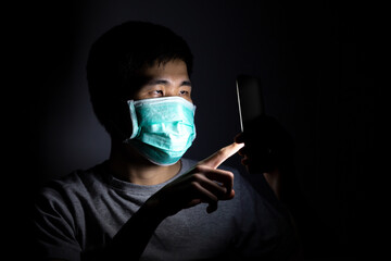 Asian man using smart phone work from home and wear a protective medical mask to prevent Coronavirus (CoVID-19) outbreak.