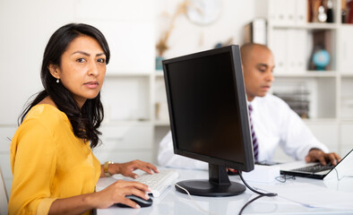 Focused hispanic business woman working with computer in modern office