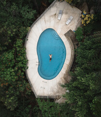 shot from a drone of a man swimming in the pool while on vacation