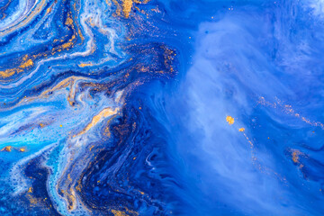 Luxury fluid art painting background. Spilled blue, white and gold acrylic paint. Liquid marble. Alcohol ink splash.