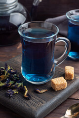 Thai blue tea anchan of buds klitoria Ternate in a glass cup, dark background.