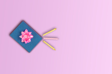 Gift box with bow surprise birthday with candles for cake on pink background copy space