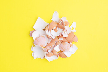 Eggshells from boiled chicken eggs on a yellow background, top view.
