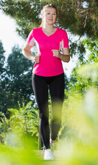Girl in pink T-shirt is training in the park.