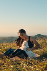 Happy young woman sitting on the grass playing with her beautiful puppy dog