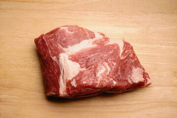 A piece of pork on a wooden chopping board. Layers of white fat are visible. Fresh meat.