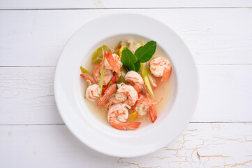Tom Yum Goong Clear Spicy Sour Soup on wooden table top view, Thai local food