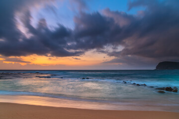 Fototapeta na wymiar Sunrise at the seaside with rain clouds rolling in