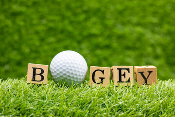 Golf bogey with golf ball and word is on green grass background. in golf, the act of getting the...