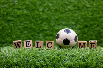 Soccer welcome sign with ball on green grass background