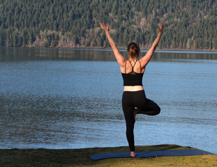 Fototapeta na wymiar Girl in yoga pose by a lake