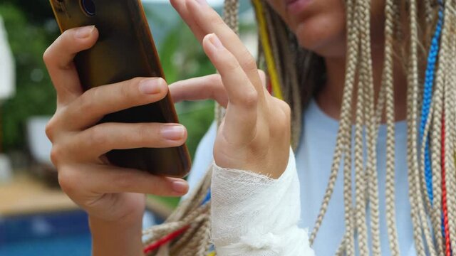 Woman's wrist with small gauze dressing or medical bandage. Female use smartphone. Social networking or social media concept. Haematoma or wound from hit hand. Victim or oppressed, joint dislocation