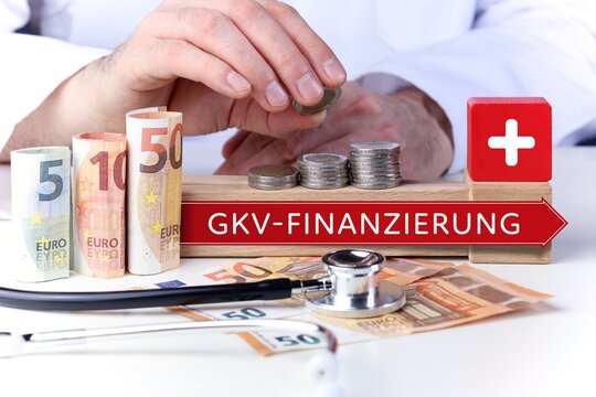 GKV-Finanzierung. Arzt stapelt Geld M&uuml;nzen auf einen Geldstapel. Text mit Begriff auf Pfeil Symbol (rot). Geldscheine & Stethoskop