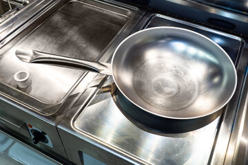 Empty frying pan in the restaurant kitchen. Metal stewpan close-up Concept - professional cookware for frying food. Professional frying pan in chrome color. Empty stewpan top view. Stewpans sale