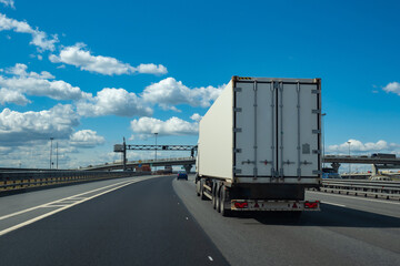 Truck is driving on a highway. Lorry with white trailer rear view. Transportation of goods with...