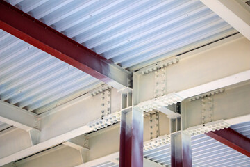  steel structure of  building with steel beams,  variety of joints and fasteners is partially covered with fire retardant materials and fire protection paint.