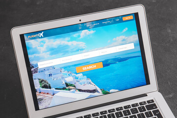 Open page of online booking service on screen of laptop on dark background