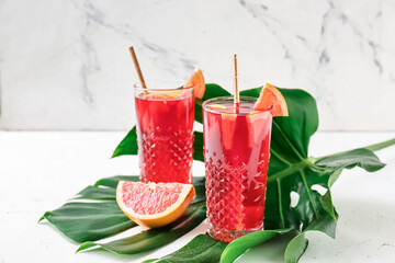 Glasses of tasty ice tea on light background