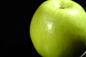 A green apple on a black background. Closeup.