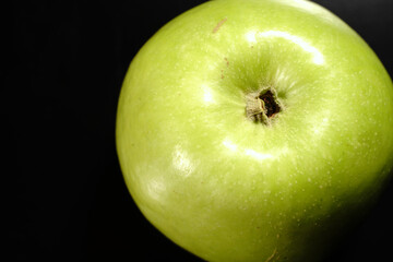 A green apple on a black background. Closeup.