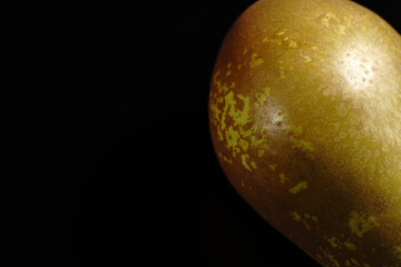 Green-brown pear on a black background. Closeup.