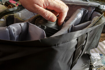 Obraz premium Man's hand places the camera lens in the section of the camera bag.