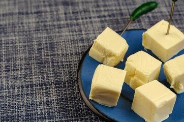 Processed cheese diced in a blue saucer.