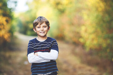 Portrait of little cool kid boy in forest. Happy healthy child having fun on warm sunny day early autumn. Family, nature, love and active leisure.