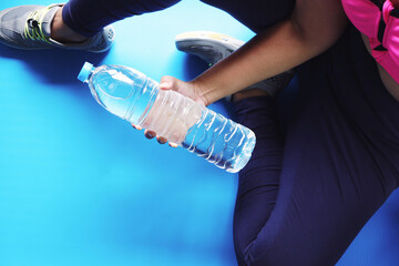 Woman excercises with water bottles at home.