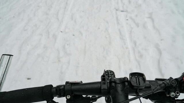 Handlebars mtb and rattling ride on trampled snow. Detail of balancing during a challenging mountain bike ride on a forest road.  Slow motion.