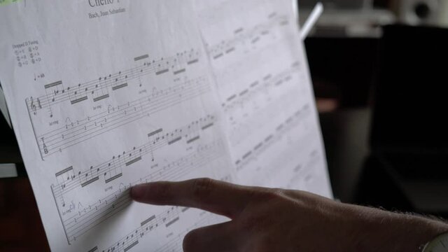 Male index finger reading sheet music on a music stand