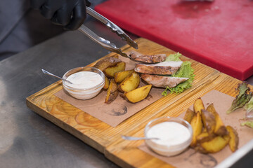 Chef lays out meat and potatoes on a wooden plate for guests in a pub