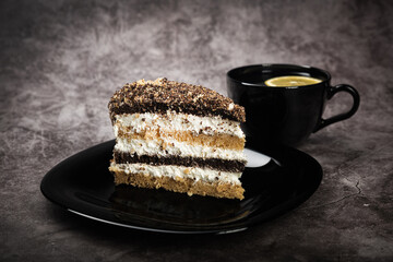 Tea with lemon and cake in a black bowl on a gray background