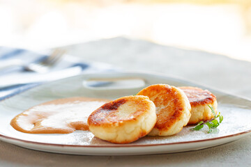 Russian cheesecakes served on plate with sauce