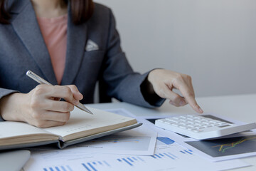 Head of accounting is recording the company's financial growth statistics using graphs as a reference for reviewing and analyzing the results, Taking notes and analyzing data graphs in office.