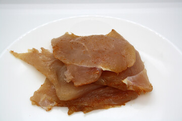 Chicken fillet pieces on a white plate.