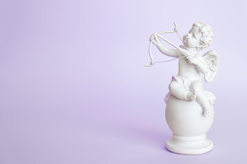 figurine of an angel Cupid with a bow on a pink background. Valentine's Day.