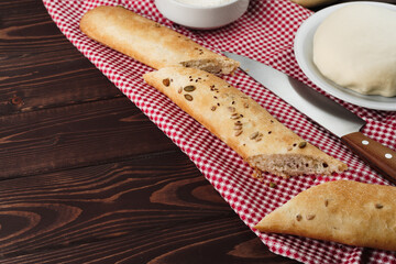 Baguette bread on brown wooden board close up