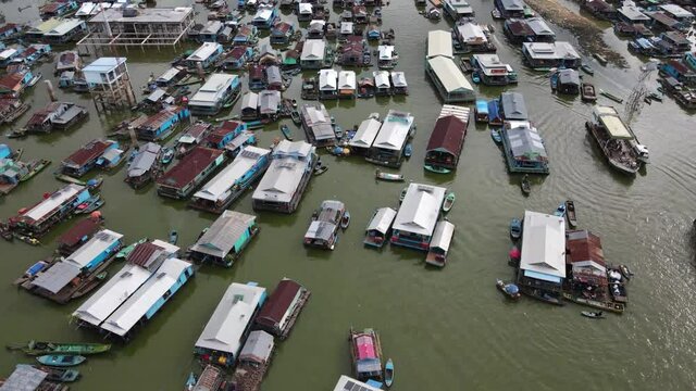 Aerial footage above a floating village along the Tonle Sap lake in Cambodia. Drone is moving backward and we can discover more houses of the typical village