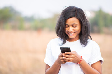 beautiful light skin african lady with freckles smiling while using her phone