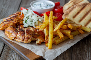 Greek dish gyros with chicken, french fries, tomatoes, onions and pita. Greek cuisine.